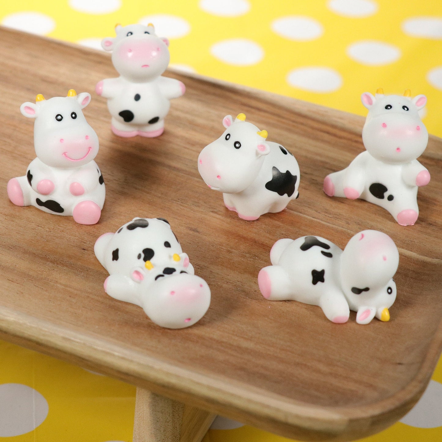 a wooden table topped with white and black cow figurines